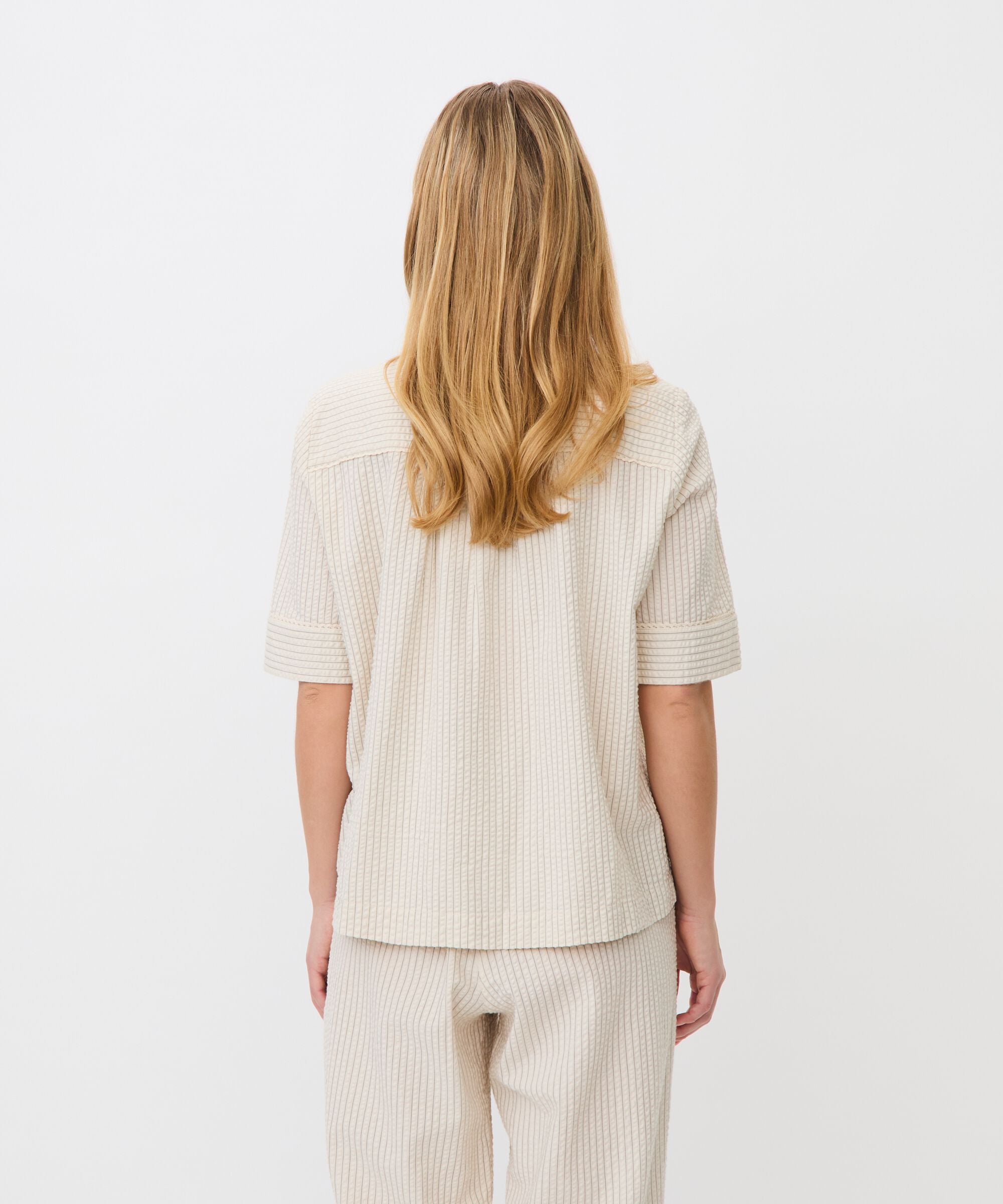 Woman wearing a beige striped outfit on a white background