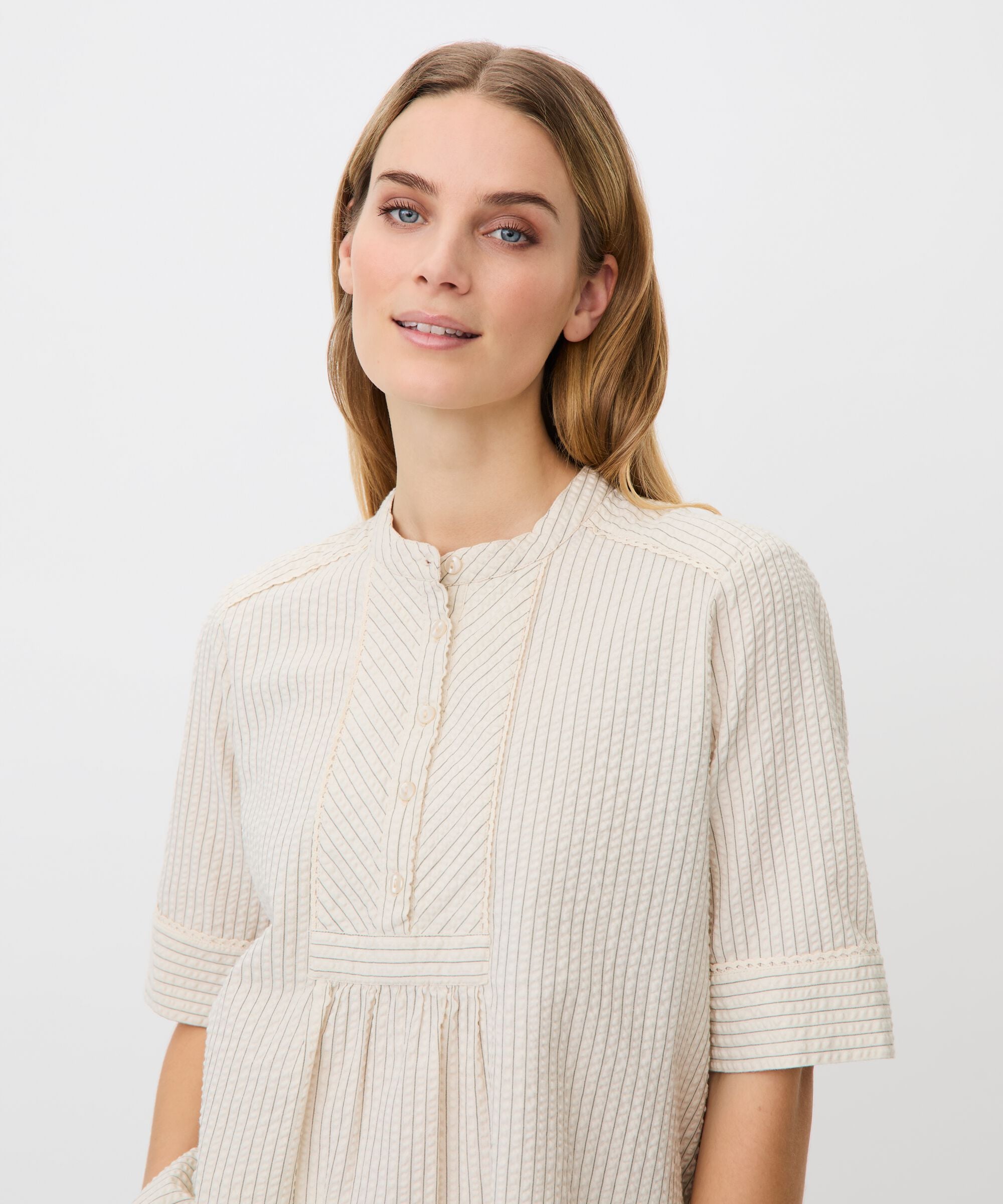 Woman wearing a beige ribbed dress against a white background