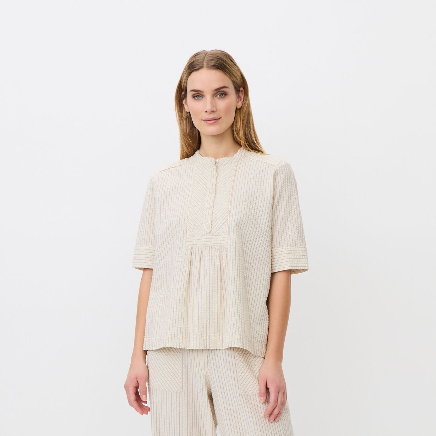Woman wearing a beige outfit on a white background