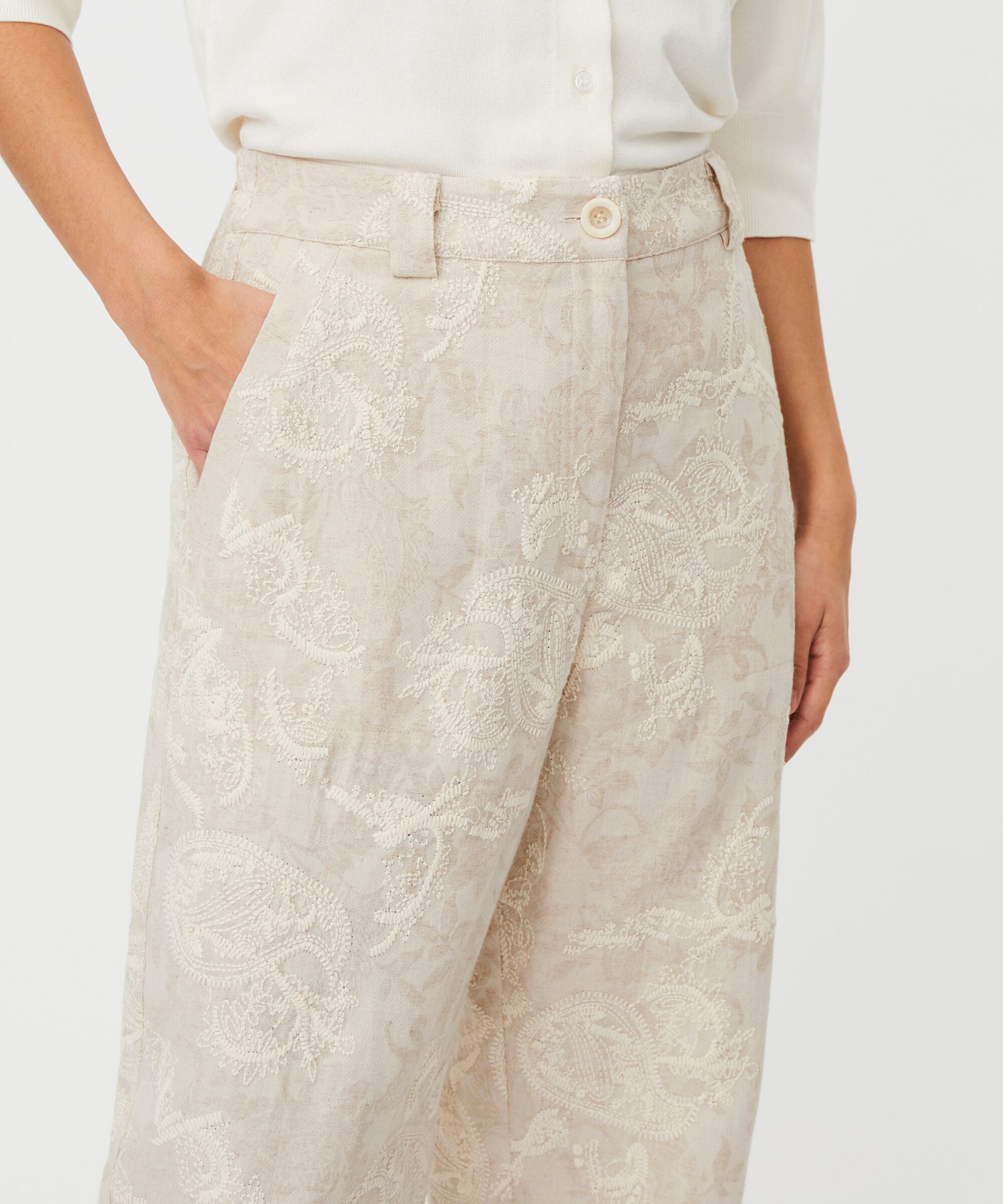 Beige patterned pants worn by a person on a white background