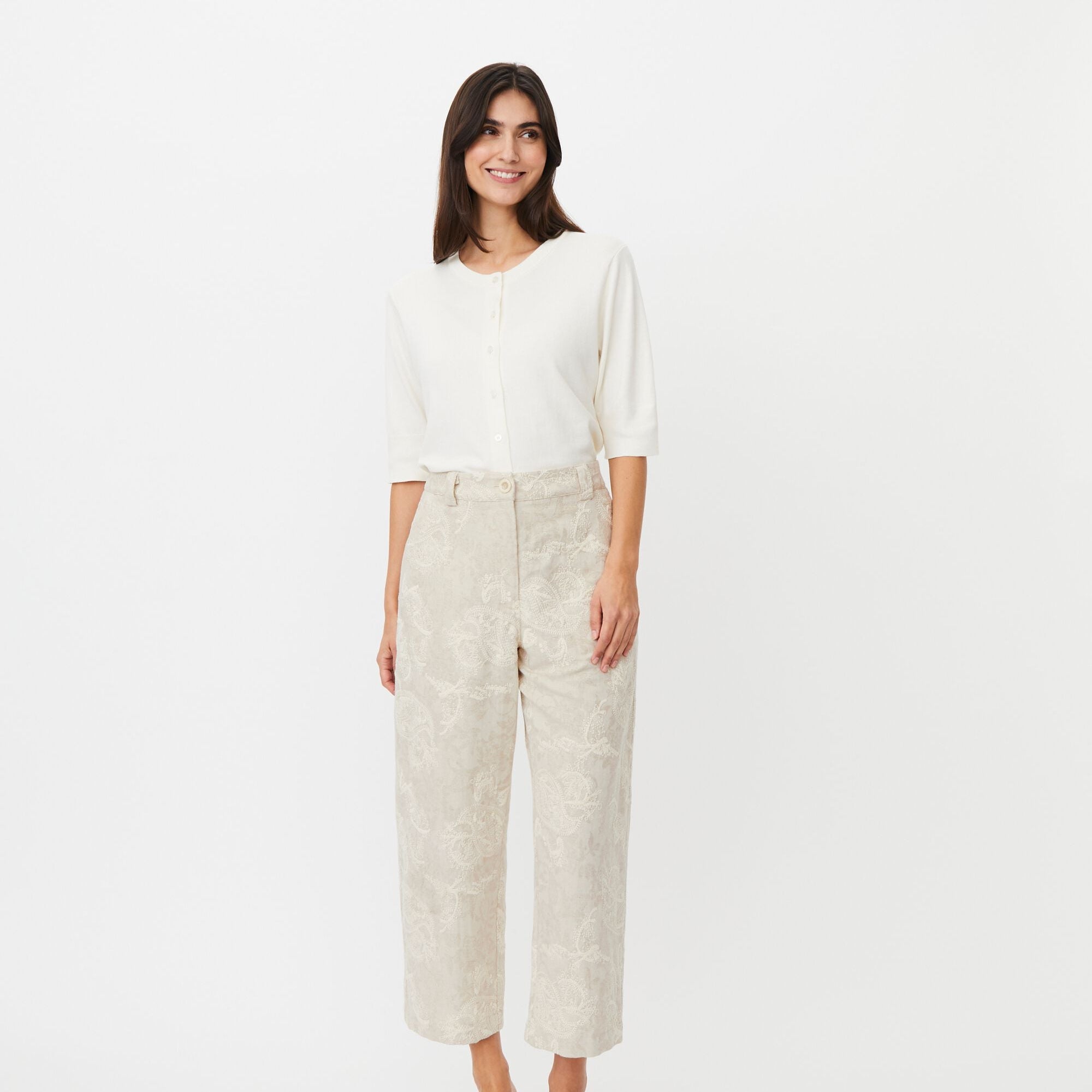 Woman wearing a white blouse and beige pants on a white background