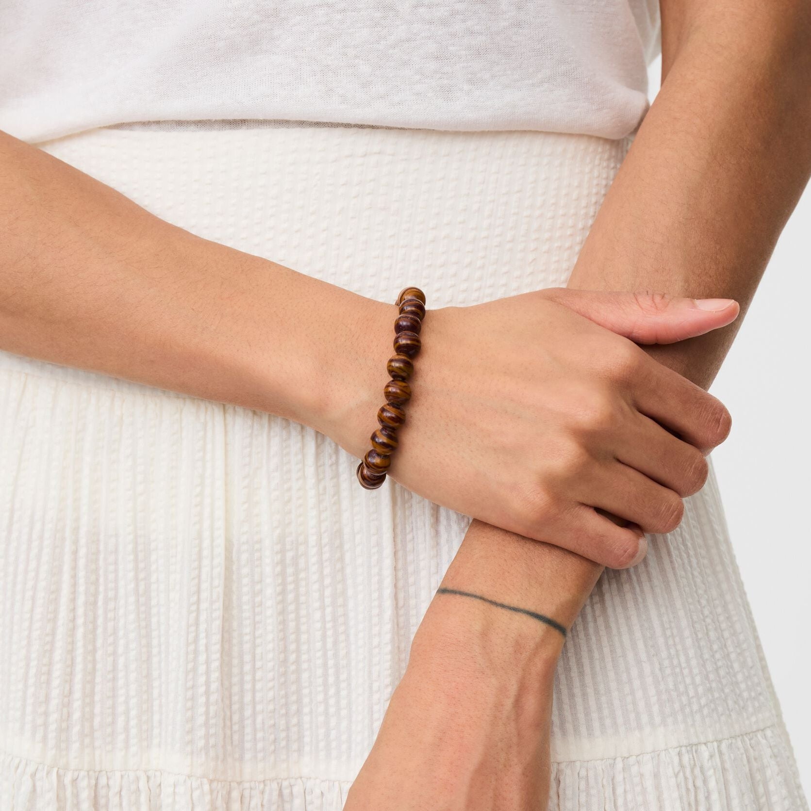 Person wearing a wooden beaded bracelet on a plain background