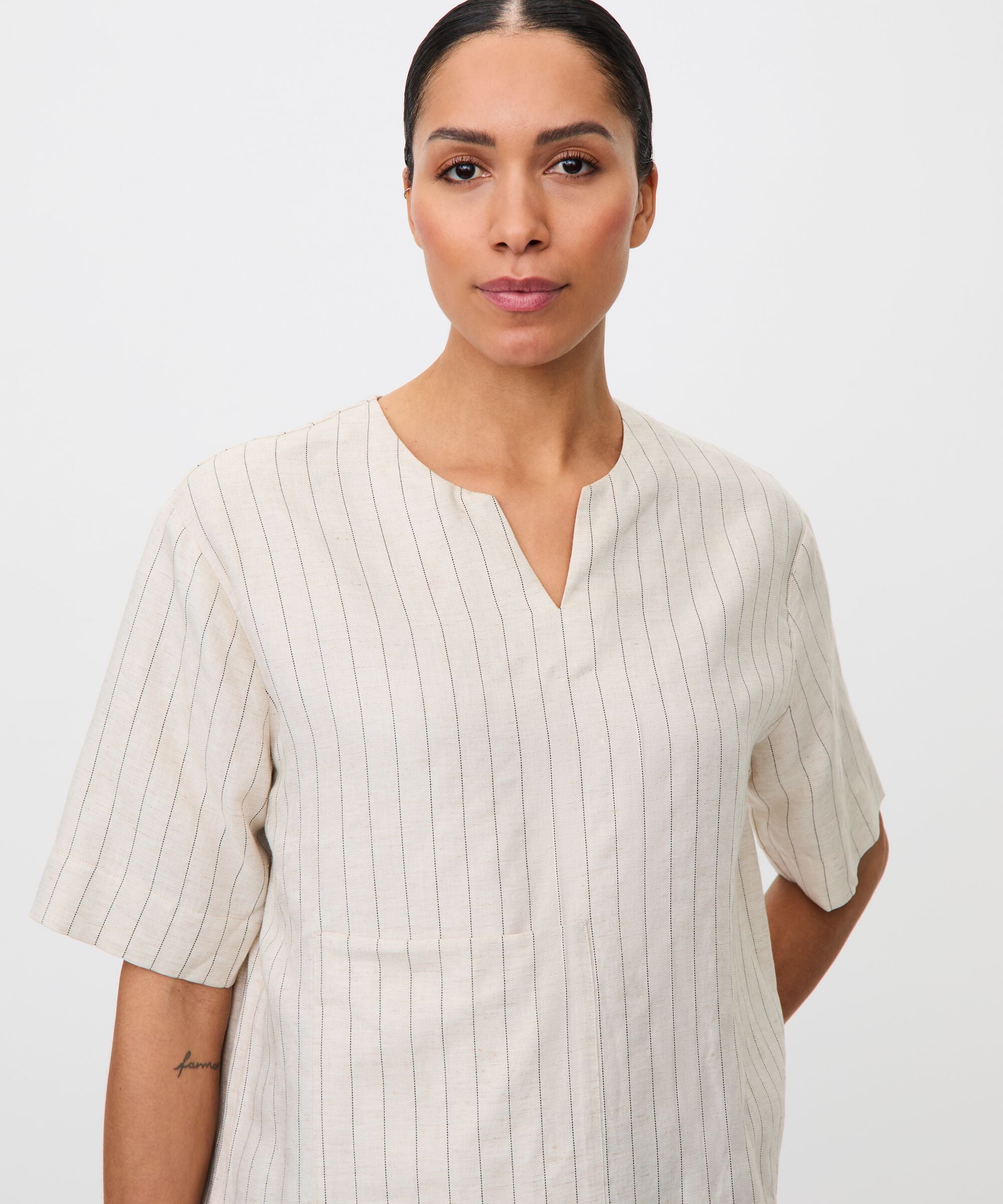 Woman wearing a white ribbed shirt against a plain background