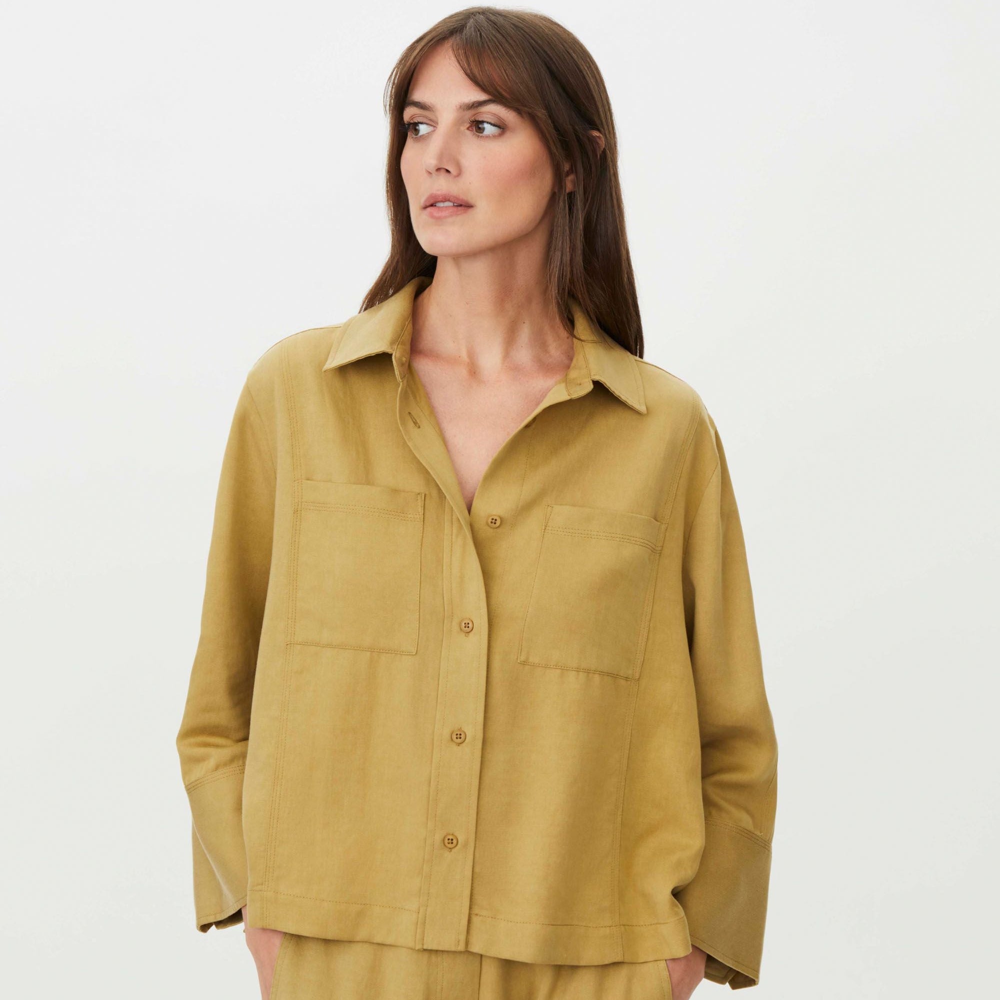 Woman wearing a mustard yellow shirt and pants on a white background