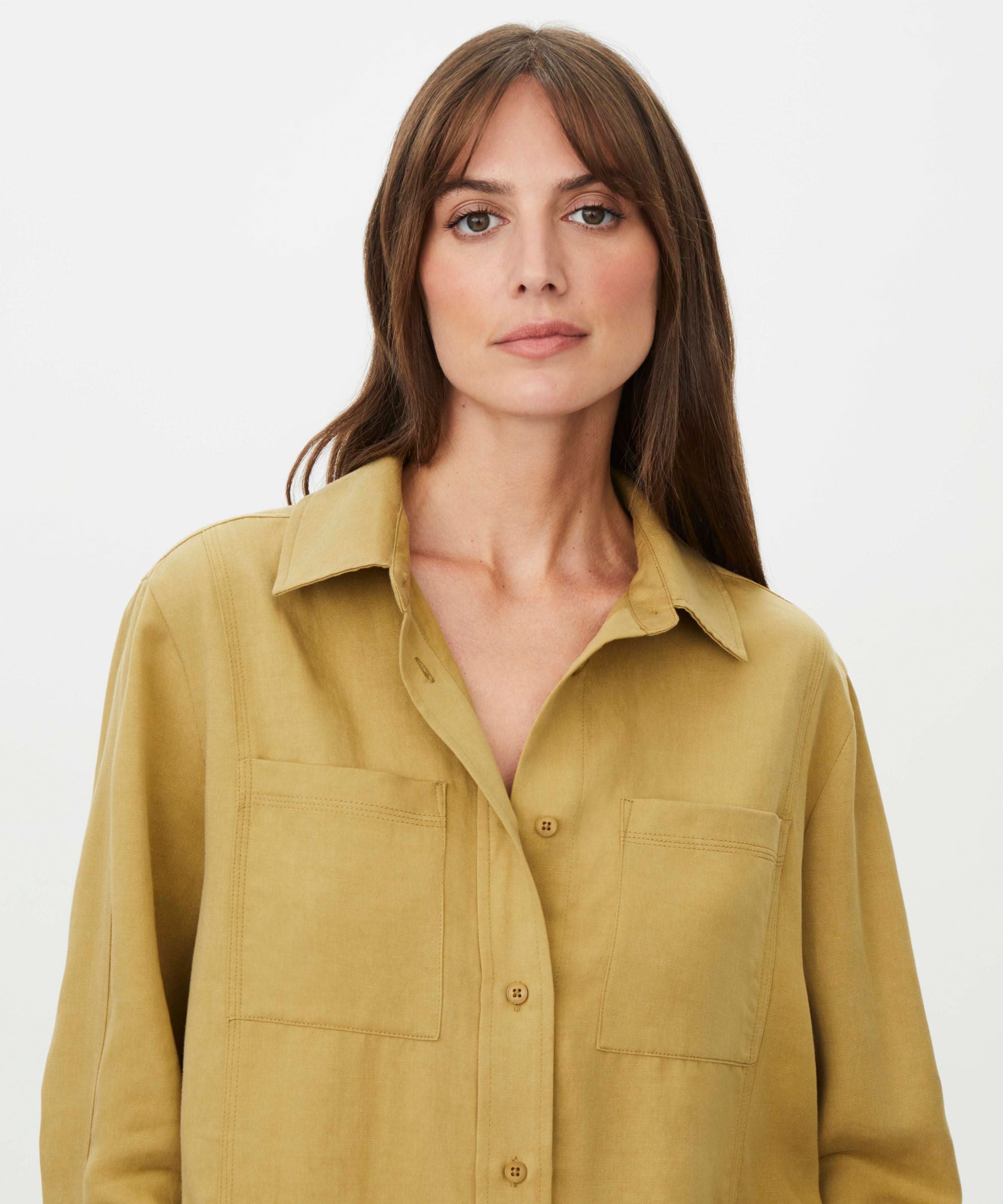 Woman wearing a mustard yellow shirt against a white background