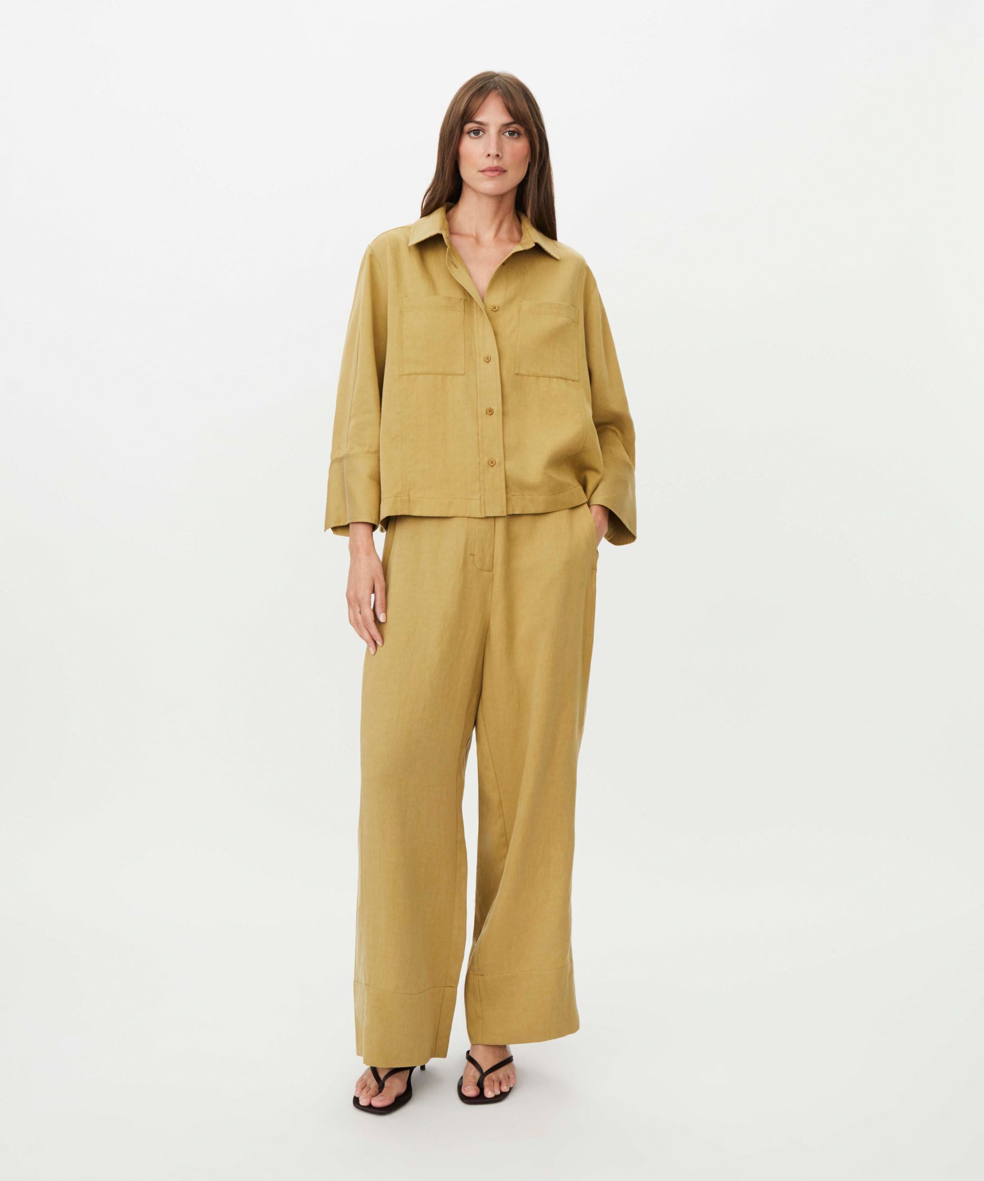Woman wearing a mustard yellow outfit on a white background