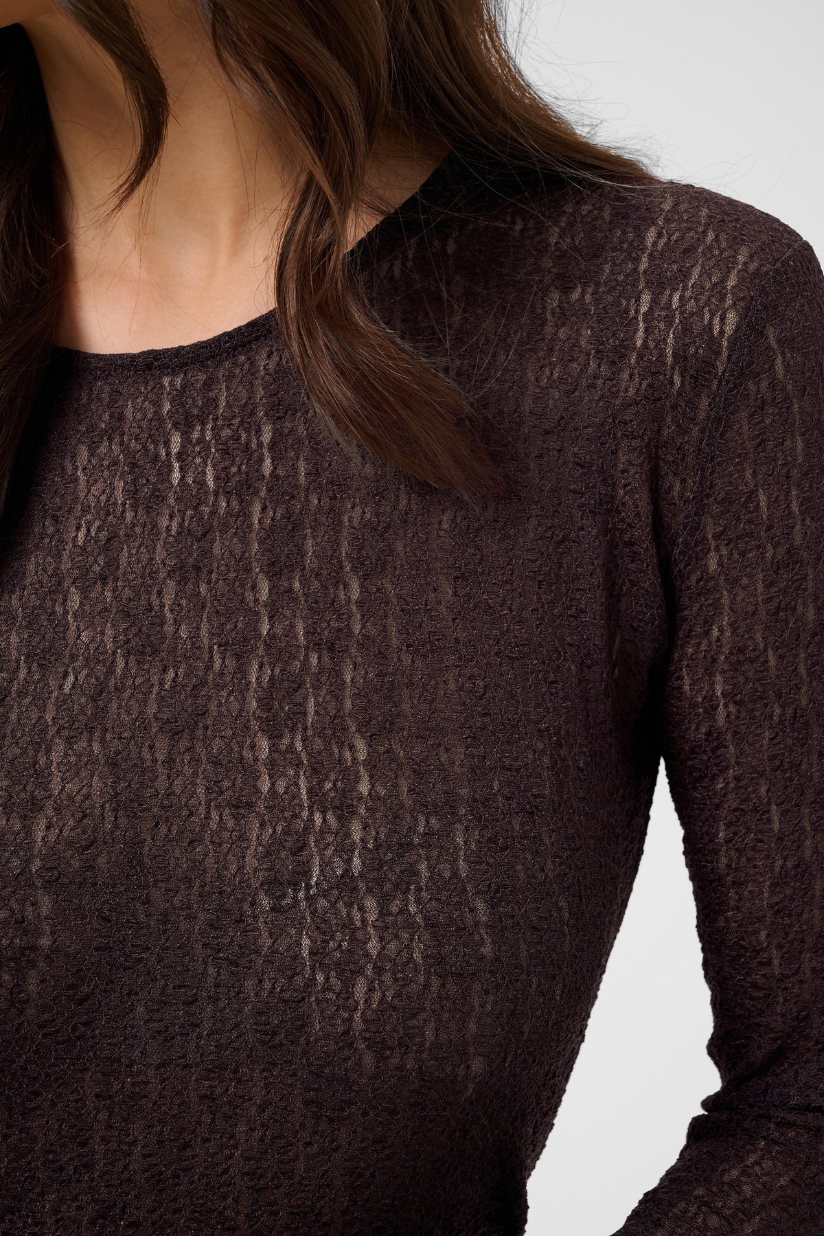 Close-up of a textured brown long-sleeve top on a plain background