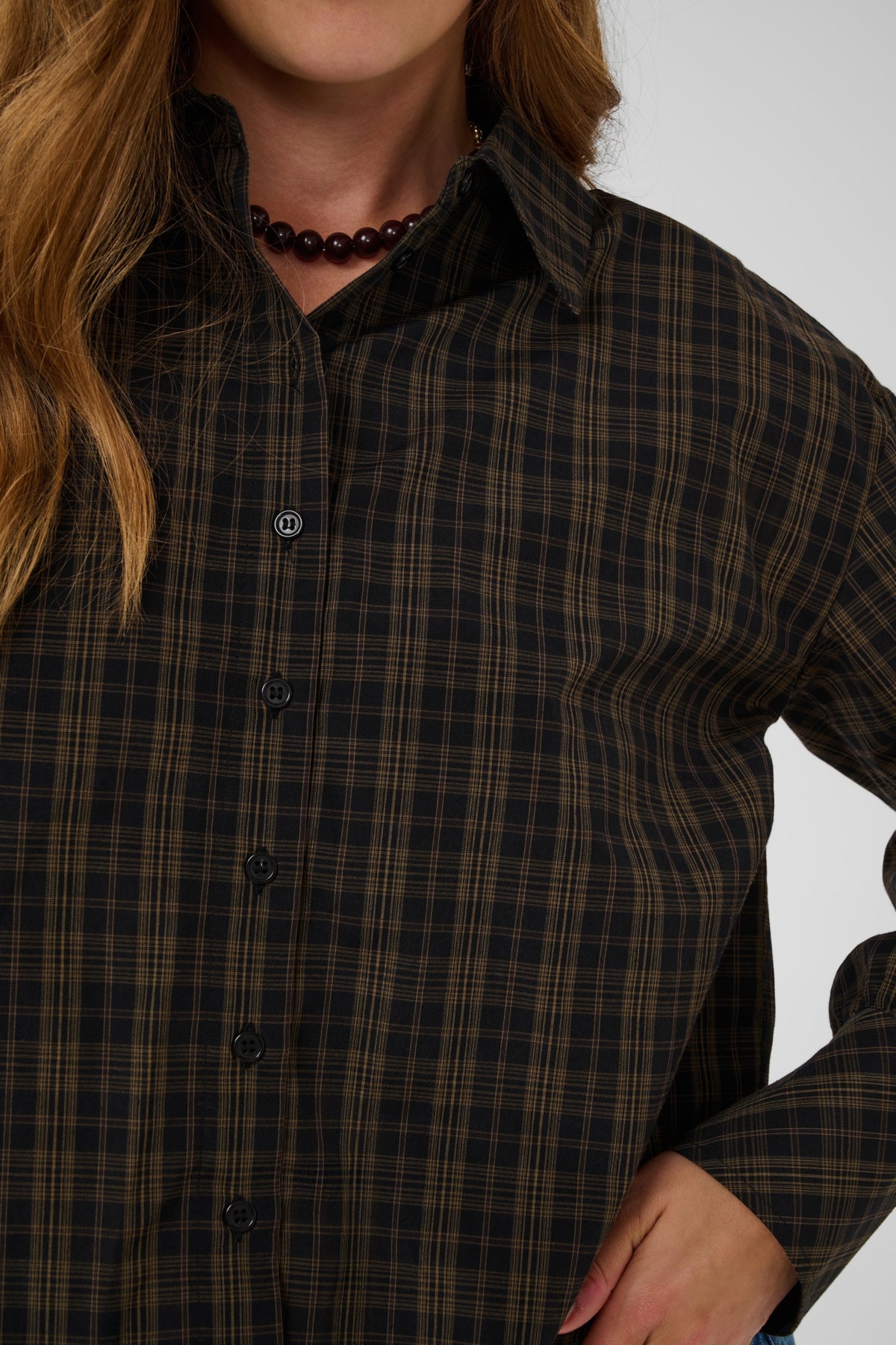 Person wearing a dark plaid shirt with a white background