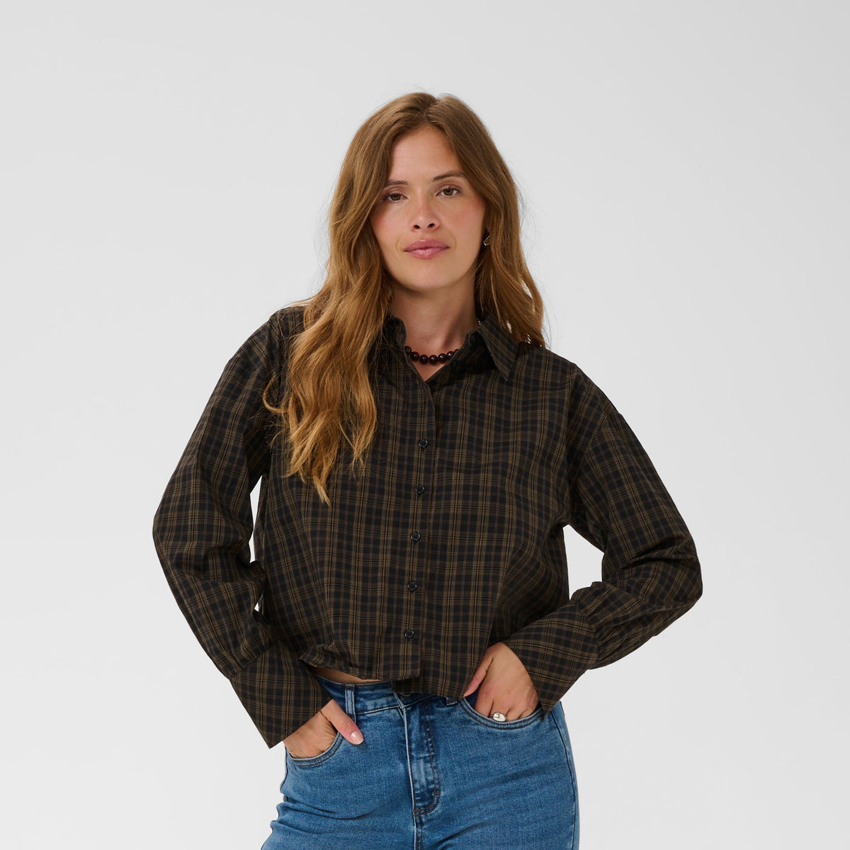 Woman wearing a plaid shirt and blue jeans on a white background