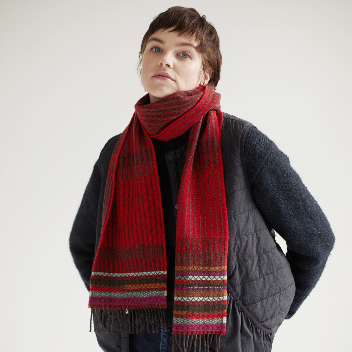 Red and brown striped wool scarf with multicolored woven border and fringe.