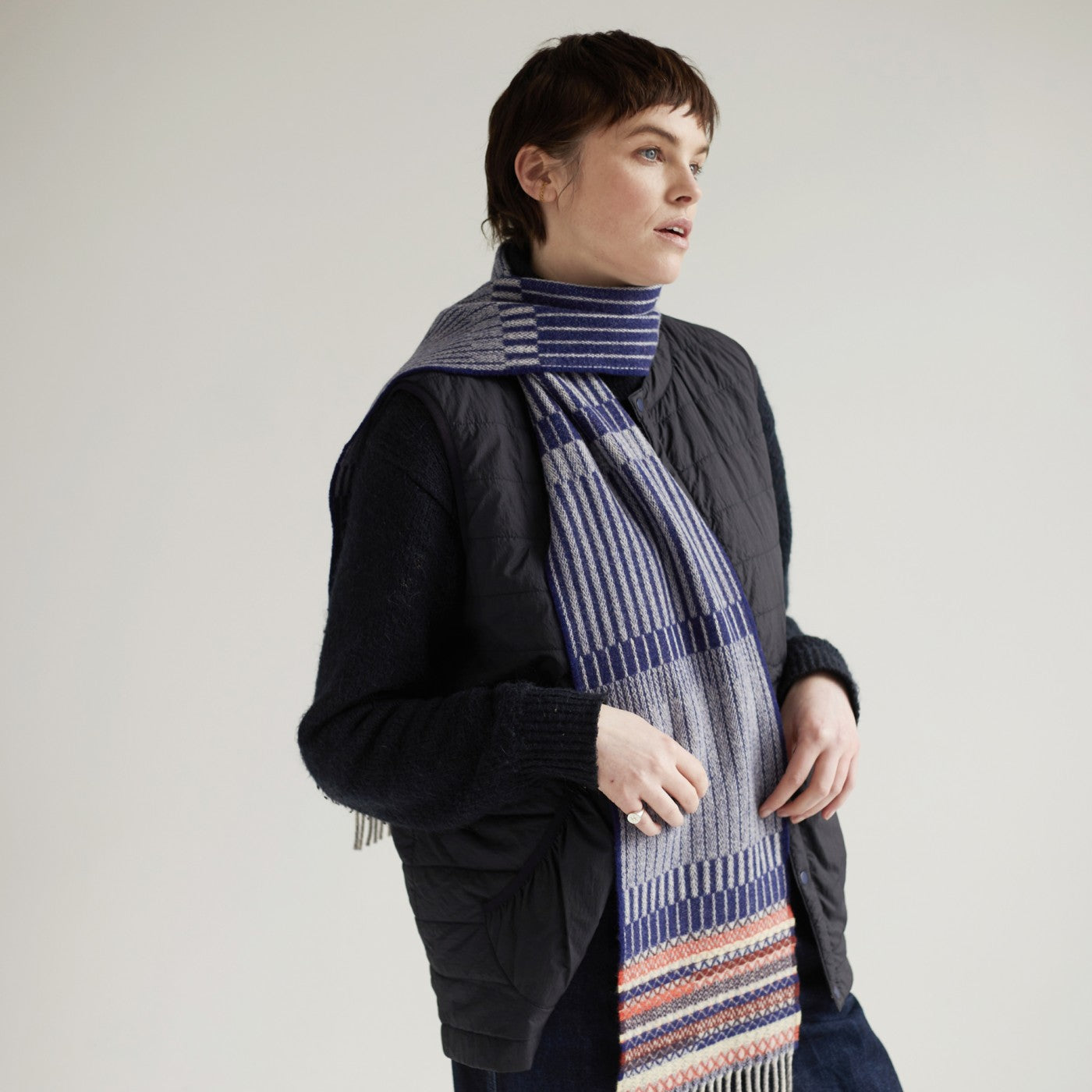 Grey and navy blue striped wool scarf with a multicolored woven band at the bottom.