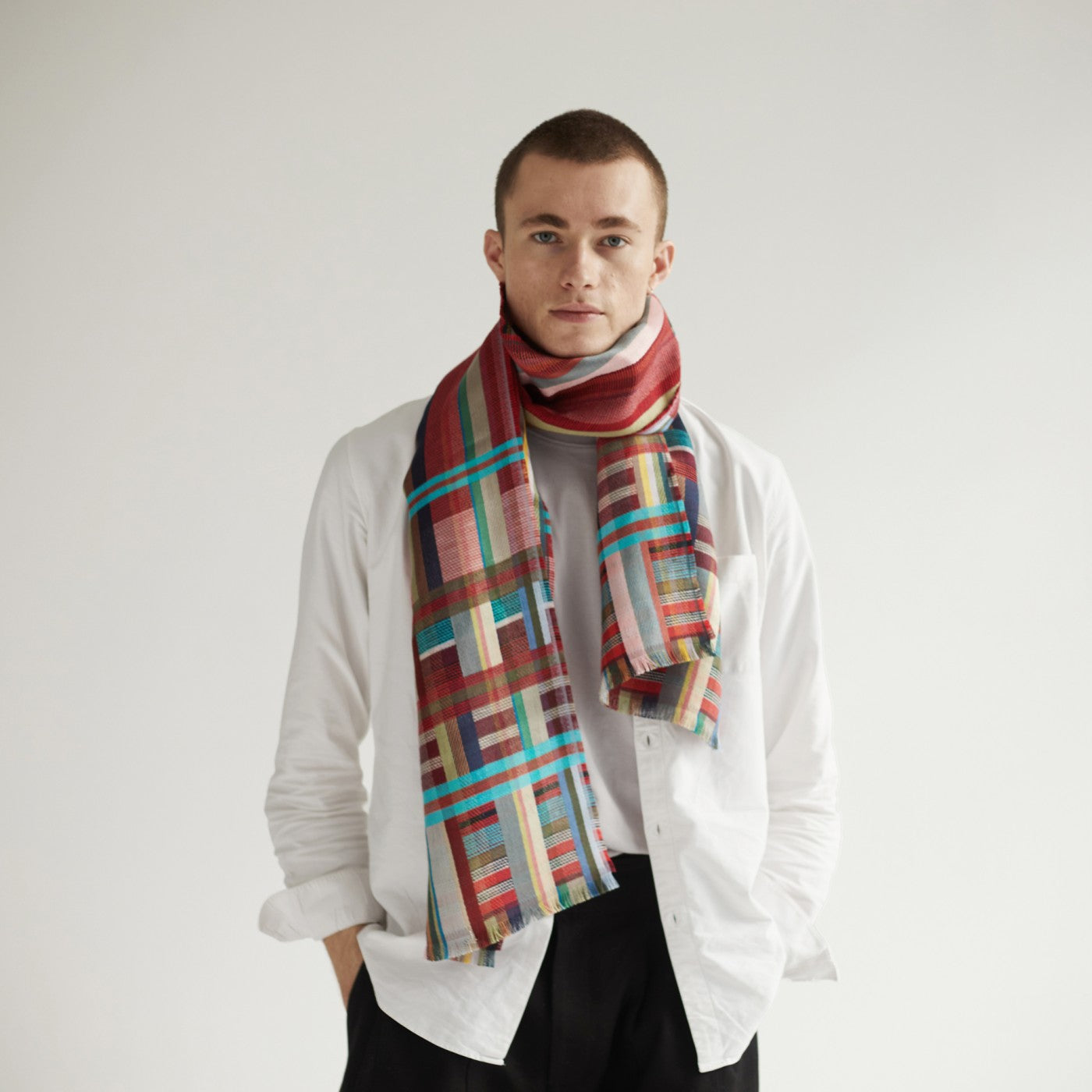 Multicolored plaid scarf with teal accents, worn by a person in a white shirt.