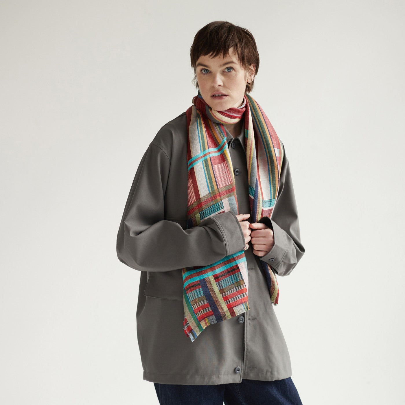 A gray work jacket with a multicolored plaid scarf.