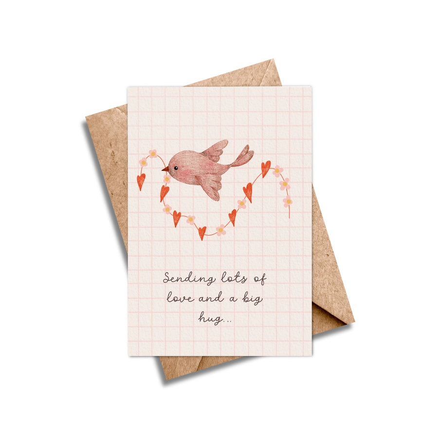 Greeting card featuring a watercolor illustration of a bird carrying a heart-shaped garland of smaller hearts and flowers.