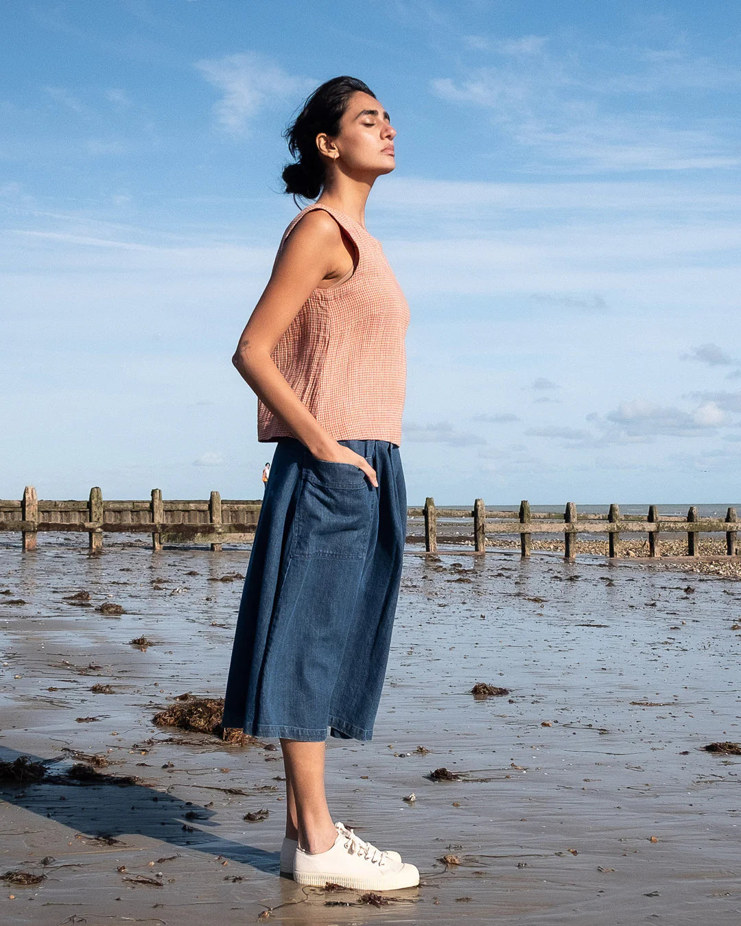 Woman standing on a beach with a clear blue sky