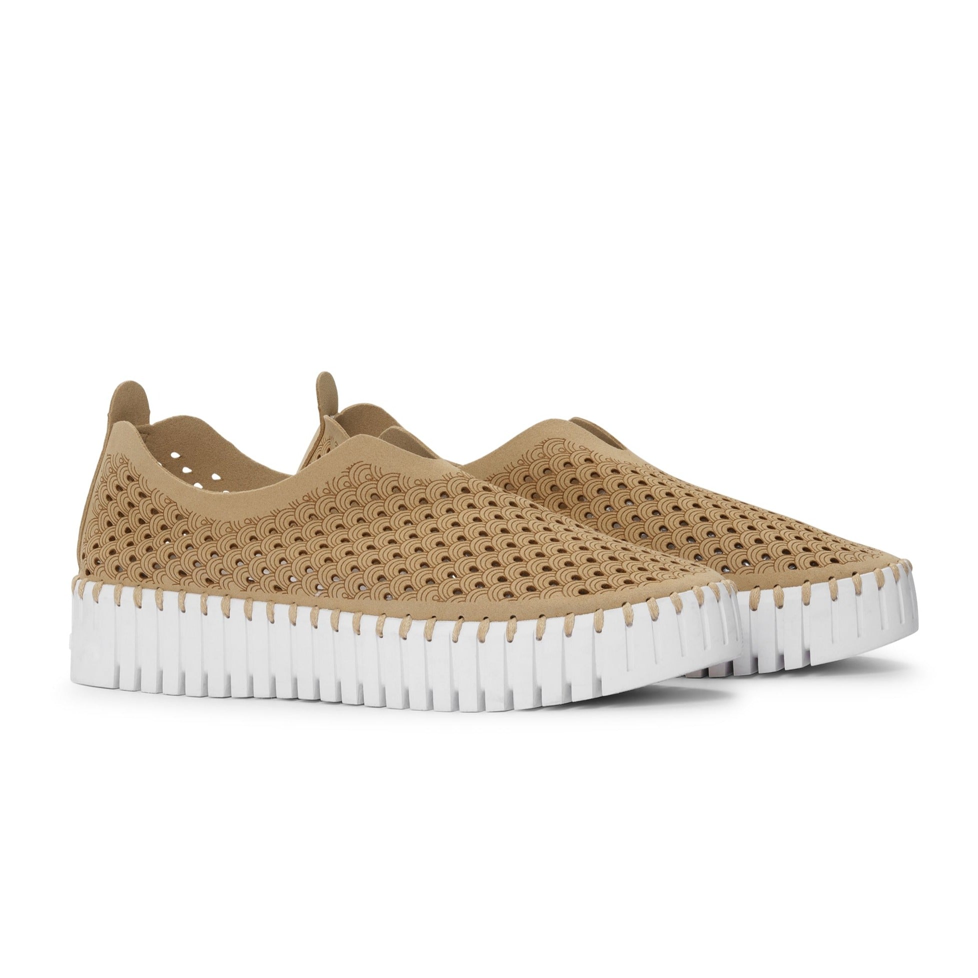 Beige slip-on shoes with a white, textured sole and a repeating wave pattern.