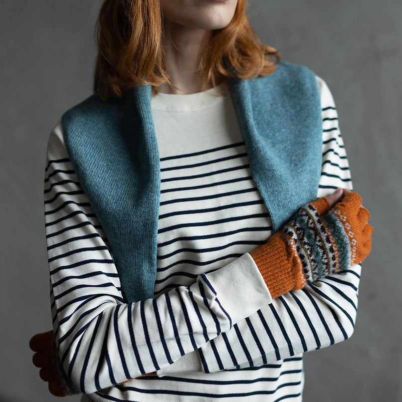 Fair isle fingerless gloves in burnt orange with teal, brown, and cream pattern.