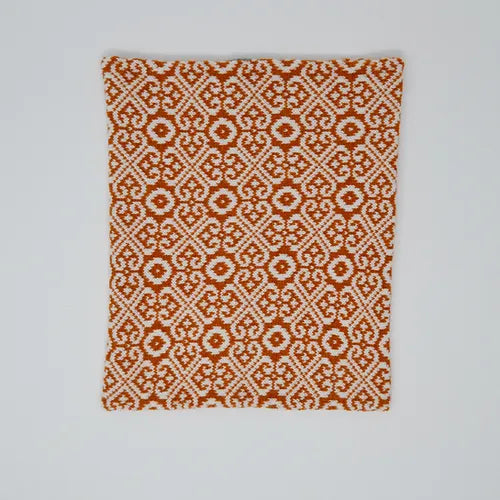 Orange and white woven textile with a repeating geometric pattern.