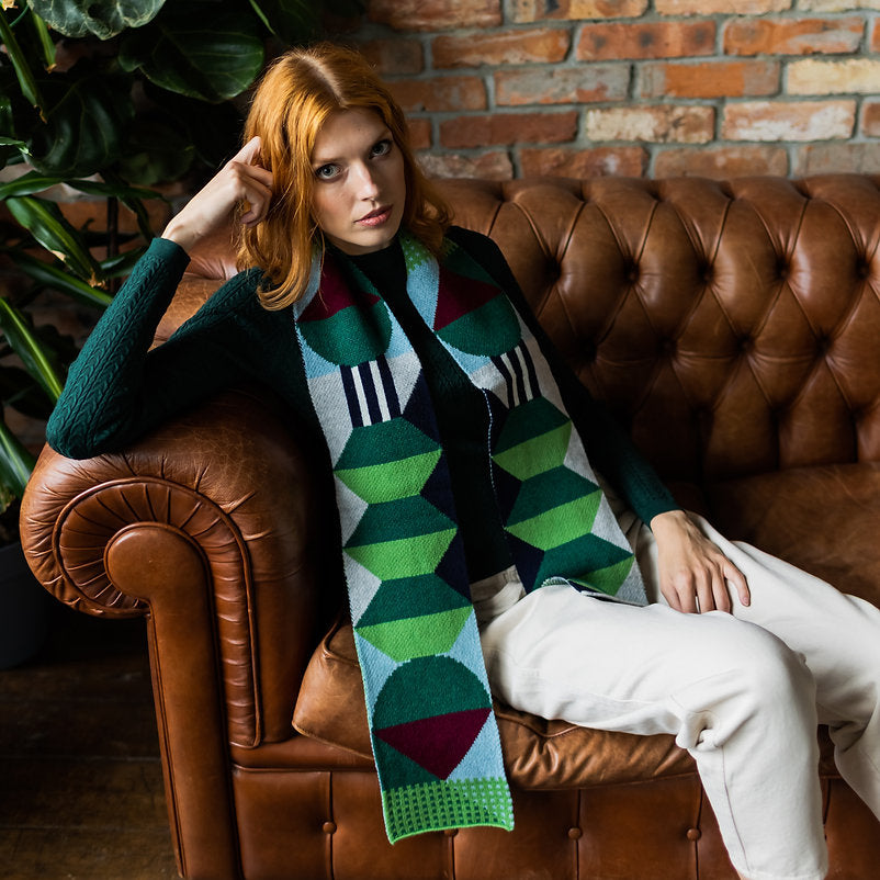 Geometric patterned scarf in greens, blues, and burgundy.  The scarf features repeating abstract shapes.