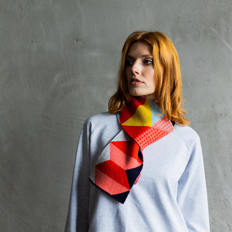 Geometric patterned knit scarf in red, pink, yellow, and navy.