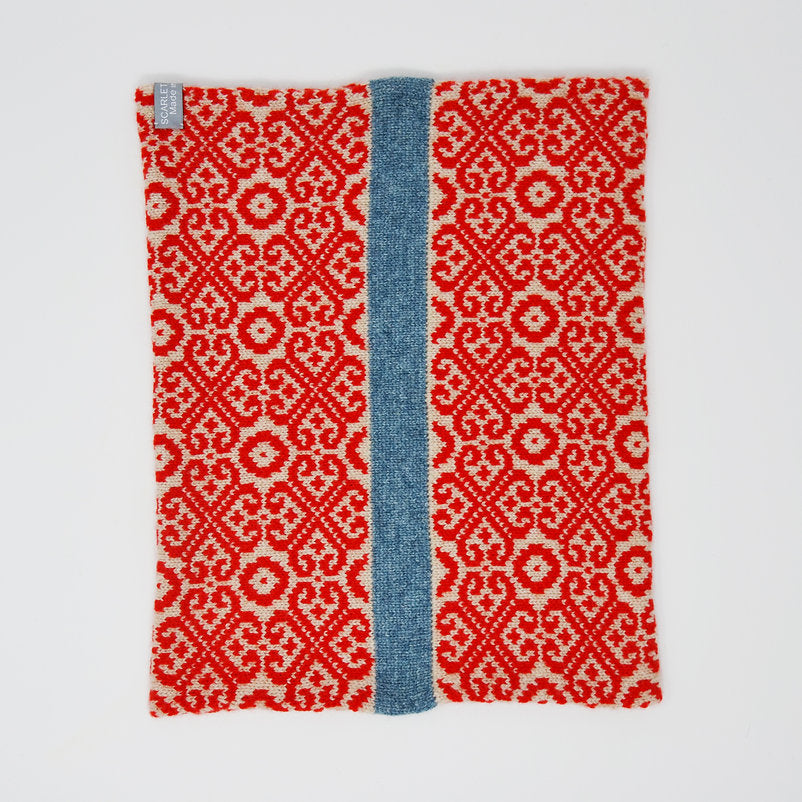 Red and cream knitted neck warmer with a central blue stripe, featuring a repeating geometric pattern.