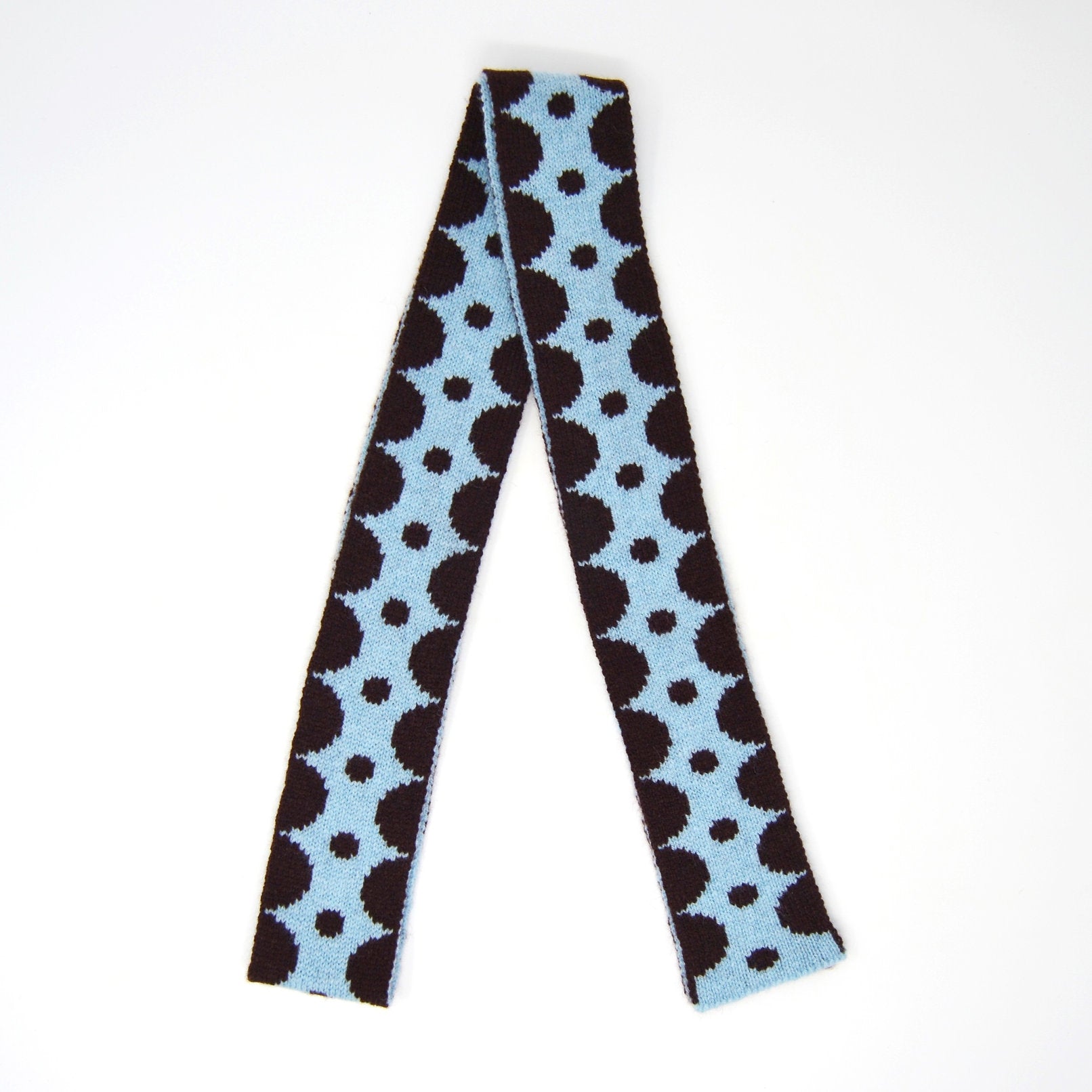 Knitted scarf with a repeating pattern of dark brown and light blue circles.