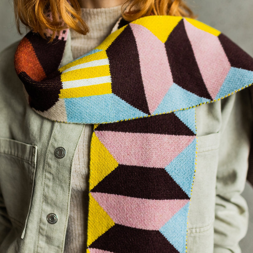 Geometric patterned knit scarf in yellow, pink, blue, and brown.