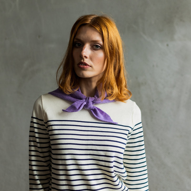 Lavender cashmere neck scarf tied around the neck of a model wearing a Breton striped top.