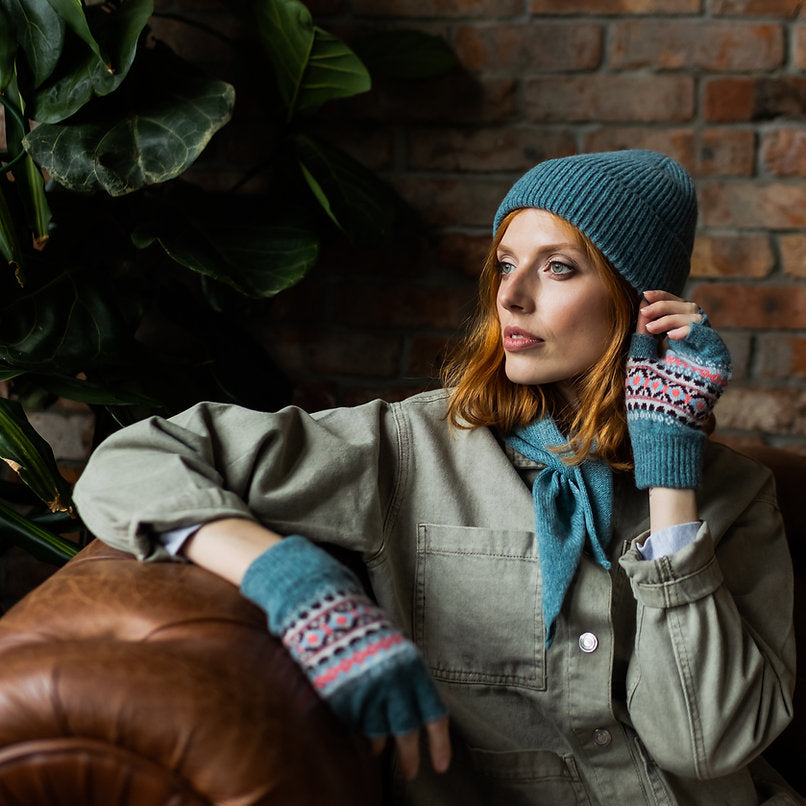 Woman wearing teal knit beanie and fingerless gloves with a Fair Isle pattern.