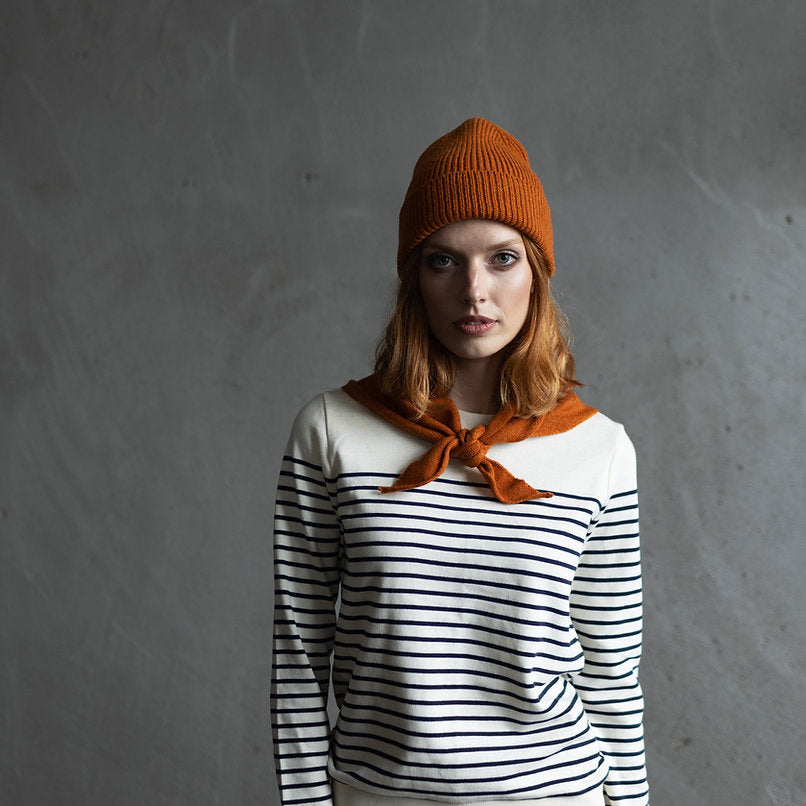 Burnt orange ribbed knit beanie and a cream and navy Breton striped long-sleeved top.