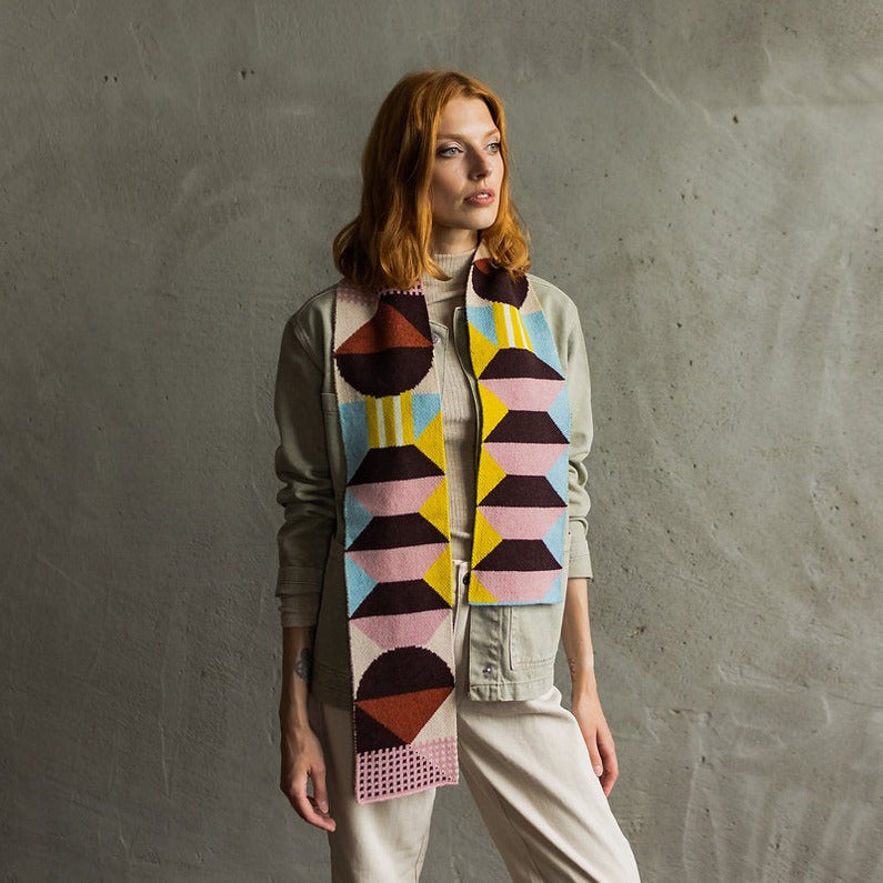 Geometric patterned knit scarf in pink, brown, yellow, and light blue.