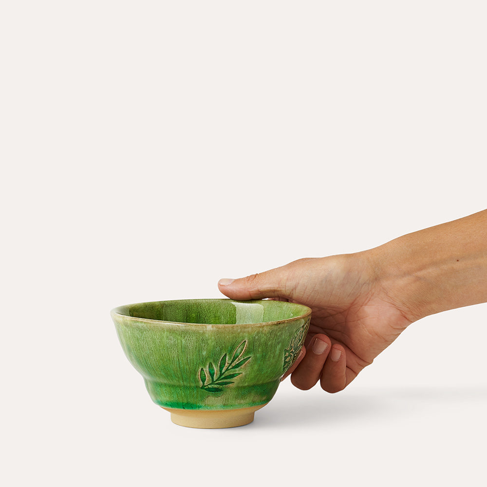 Green ceramic bowl with leaf design, slightly flared rim, and a light beige base.