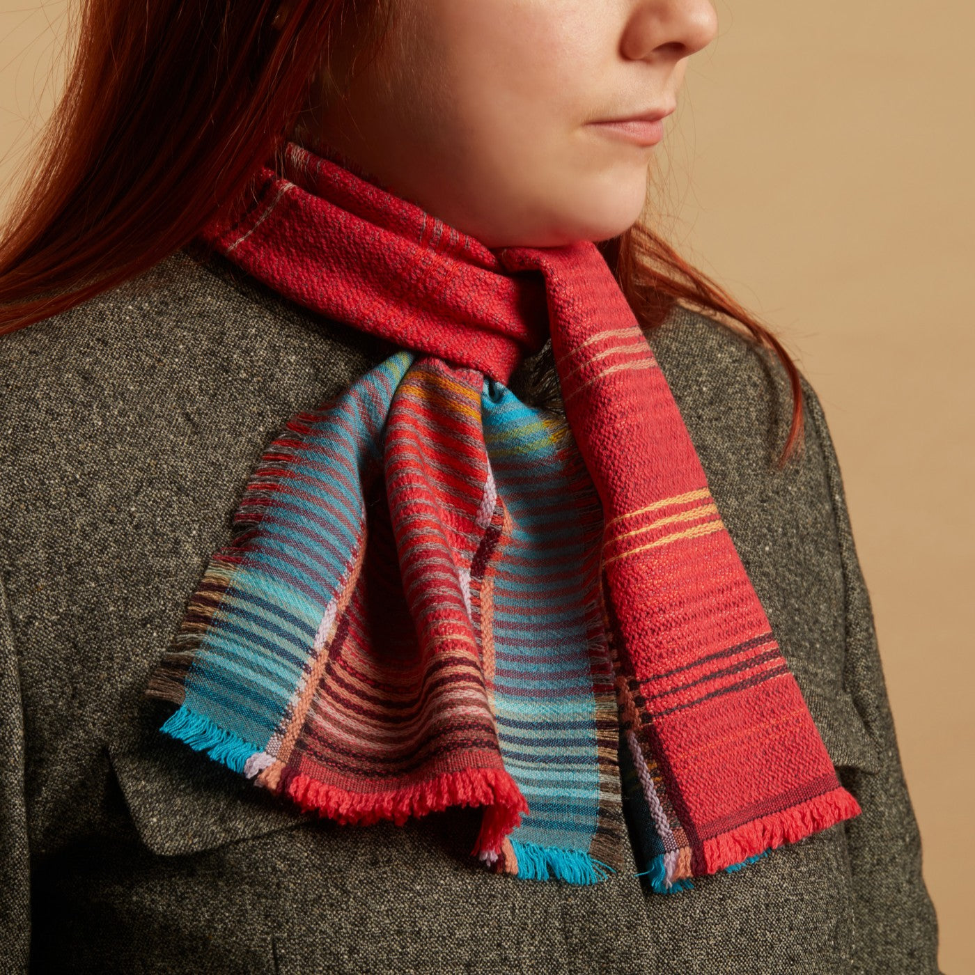 Person wearing a colorful striped scarf with a neutral background