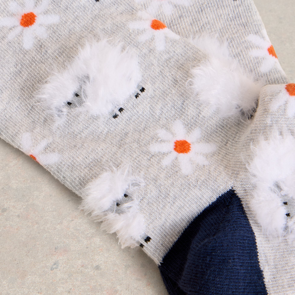 Grey socks with fuzzy sheep and orange-centered daisy patterns.