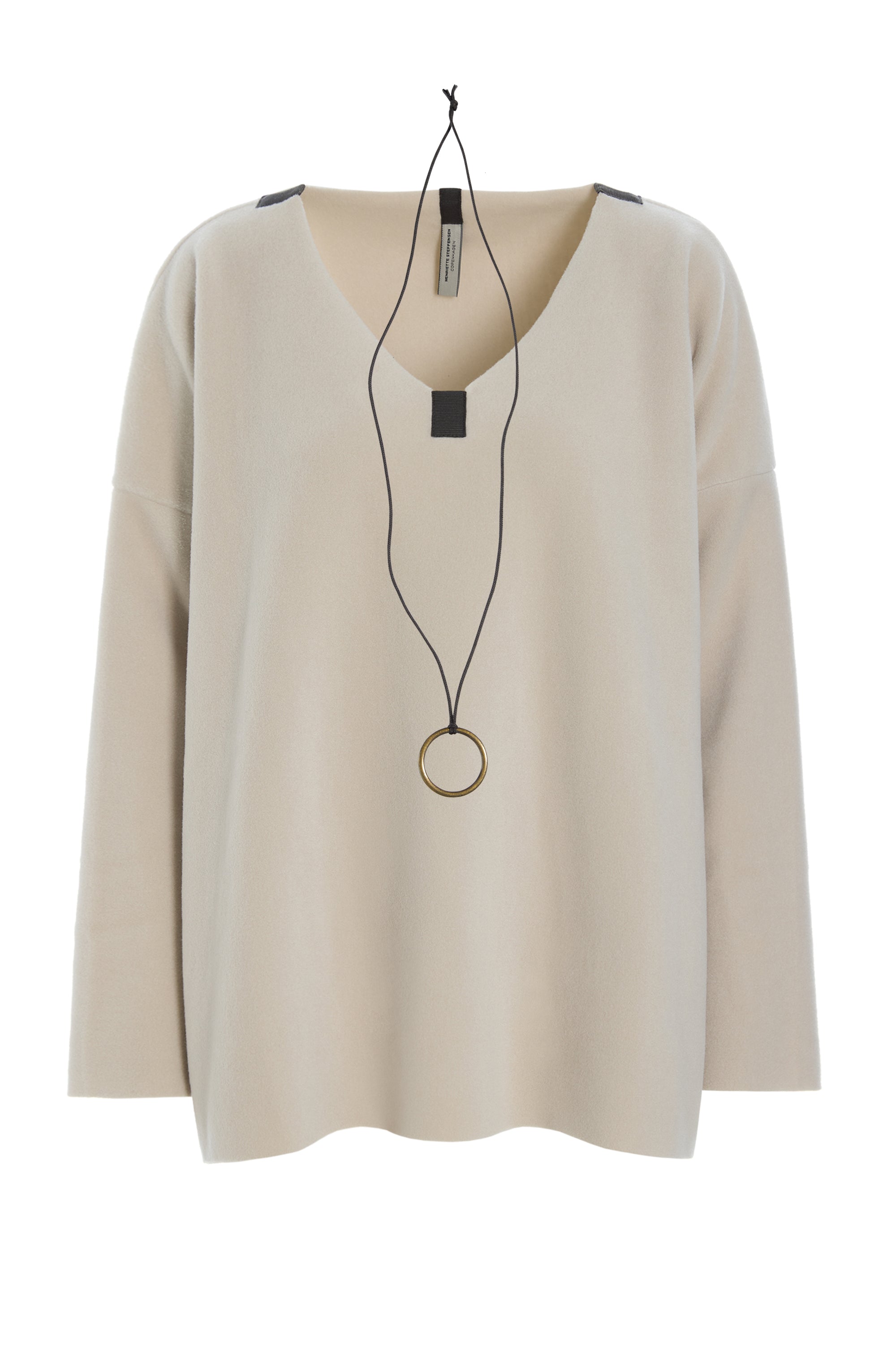 A beige long-sleeve knit top with a V-neck, shown hanging on a black hanger with a long black cord necklace draped over the front.