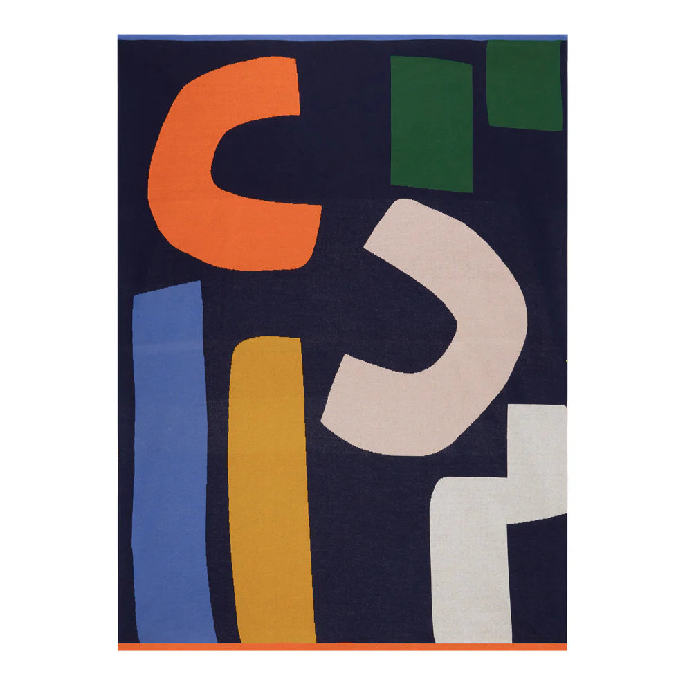 Abstract throw blanket with navy blue background and multicolored geometric shapes in orange, pink, yellow, green, and blue.