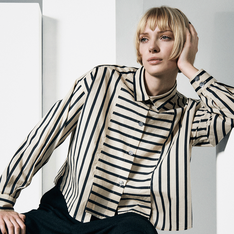 Person wearing a black and white striped shirt and dark pants against a white background
