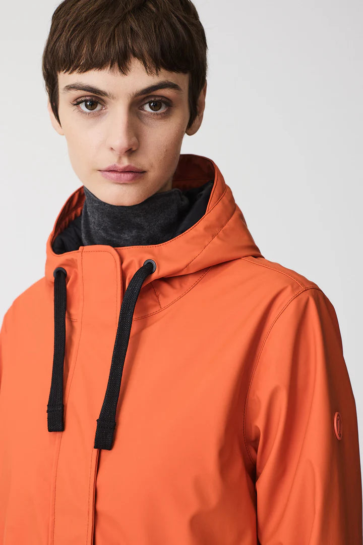Person wearing an orange jacket with a black hood against a white background