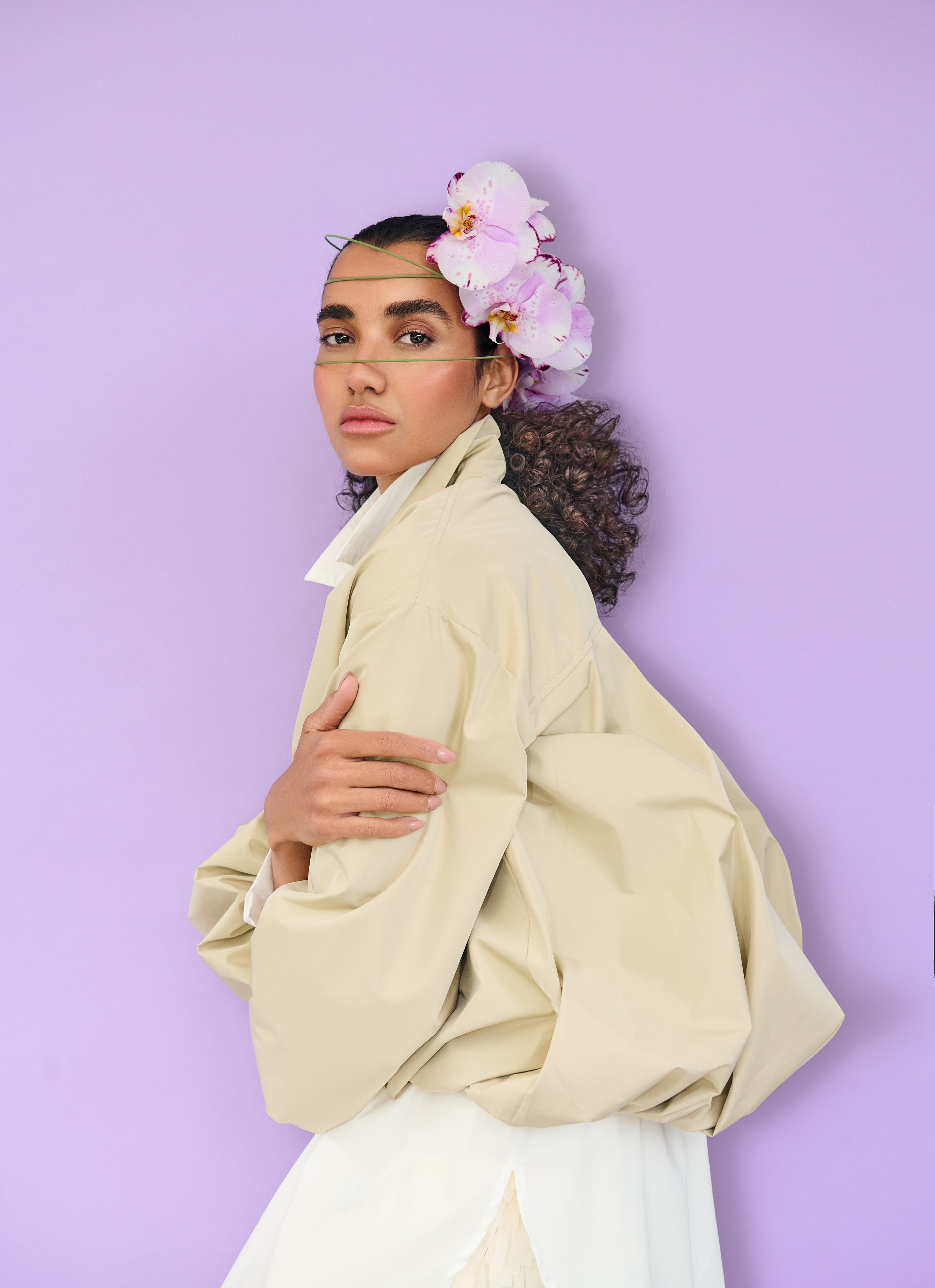 Person wearing a beige jacket with a purple background