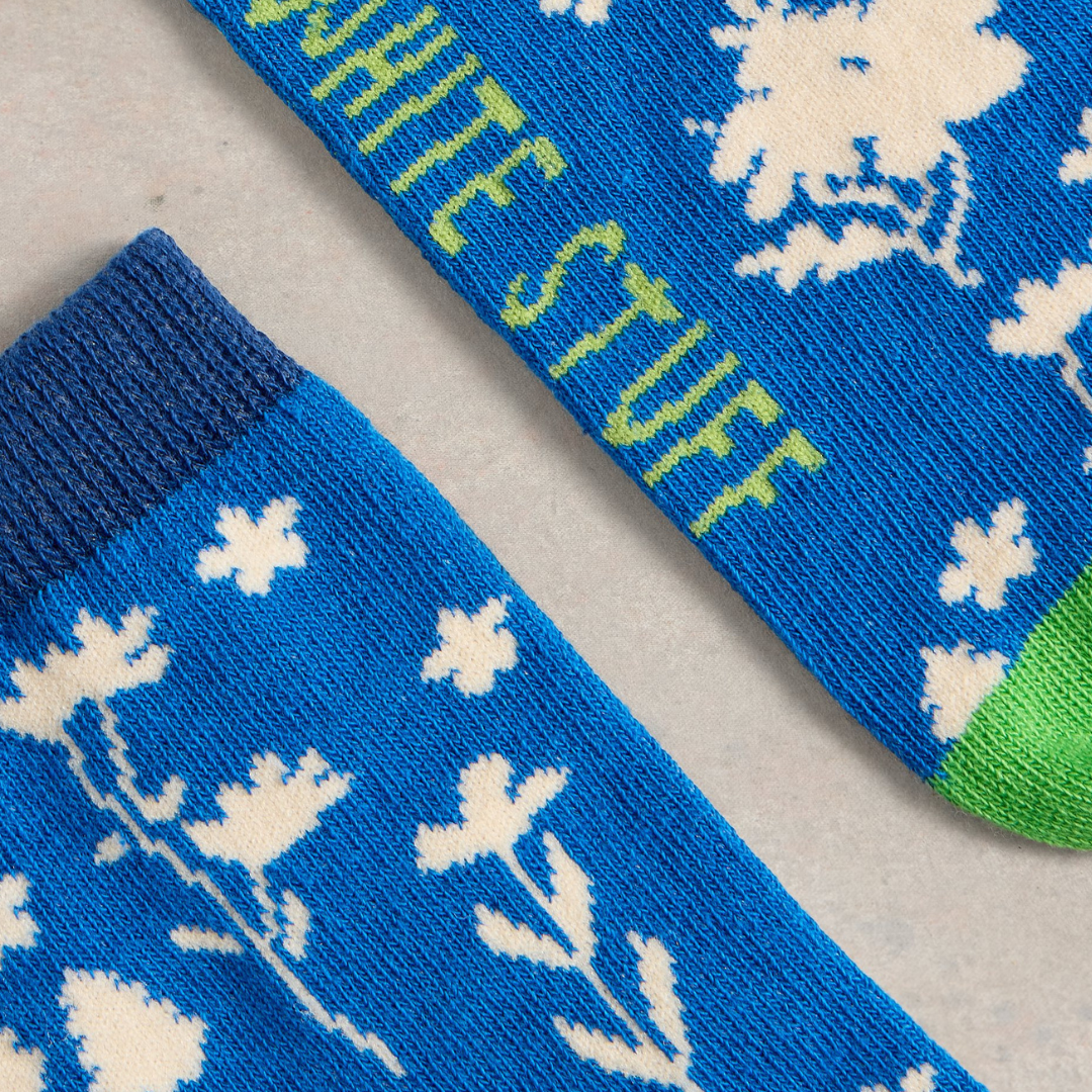 Pair of blue socks with a white floral pattern and partial "White Stuff" text visible.