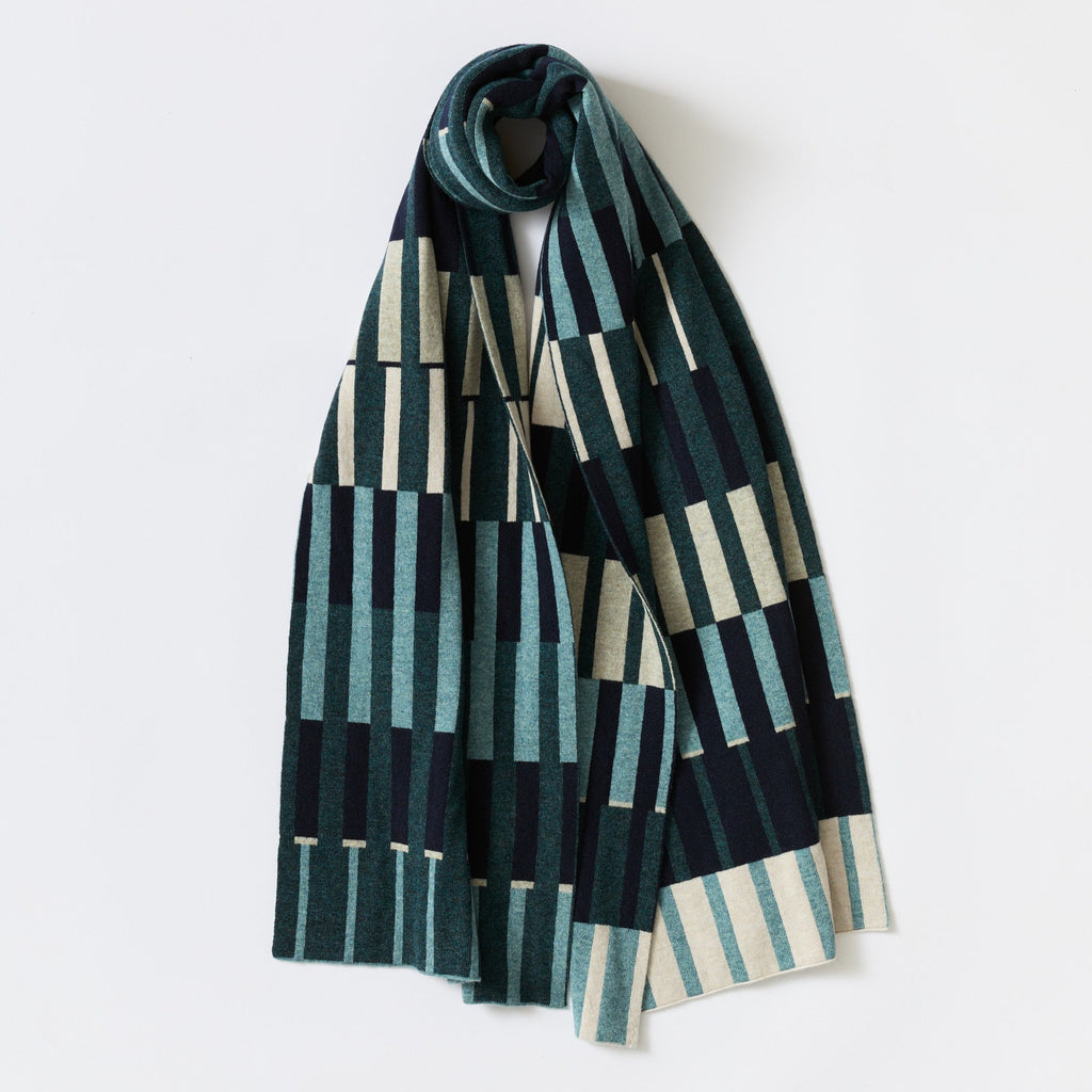Knit scarf with teal, navy, and cream vertical stripes forming a geometric pattern.