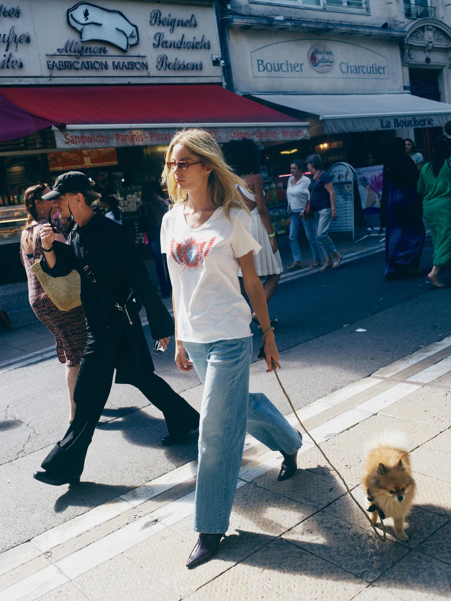 Woman walking a dog on a city street with shops and pedestrians in the background