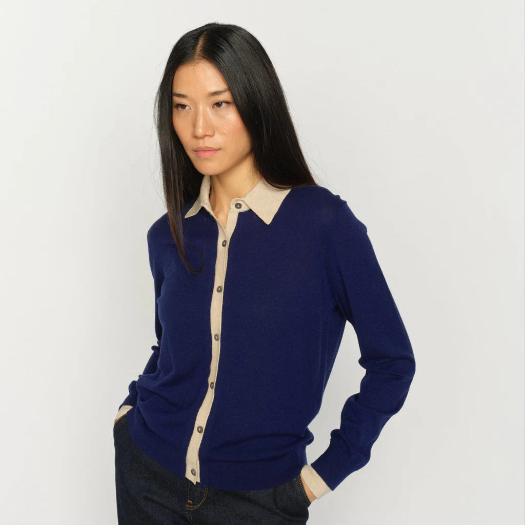 Woman wearing a blue long-sleeve shirt with a beige collar against a white background