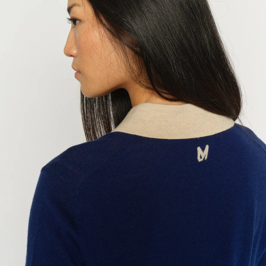 Woman wearing a blue sweater with a beige collar against a white background