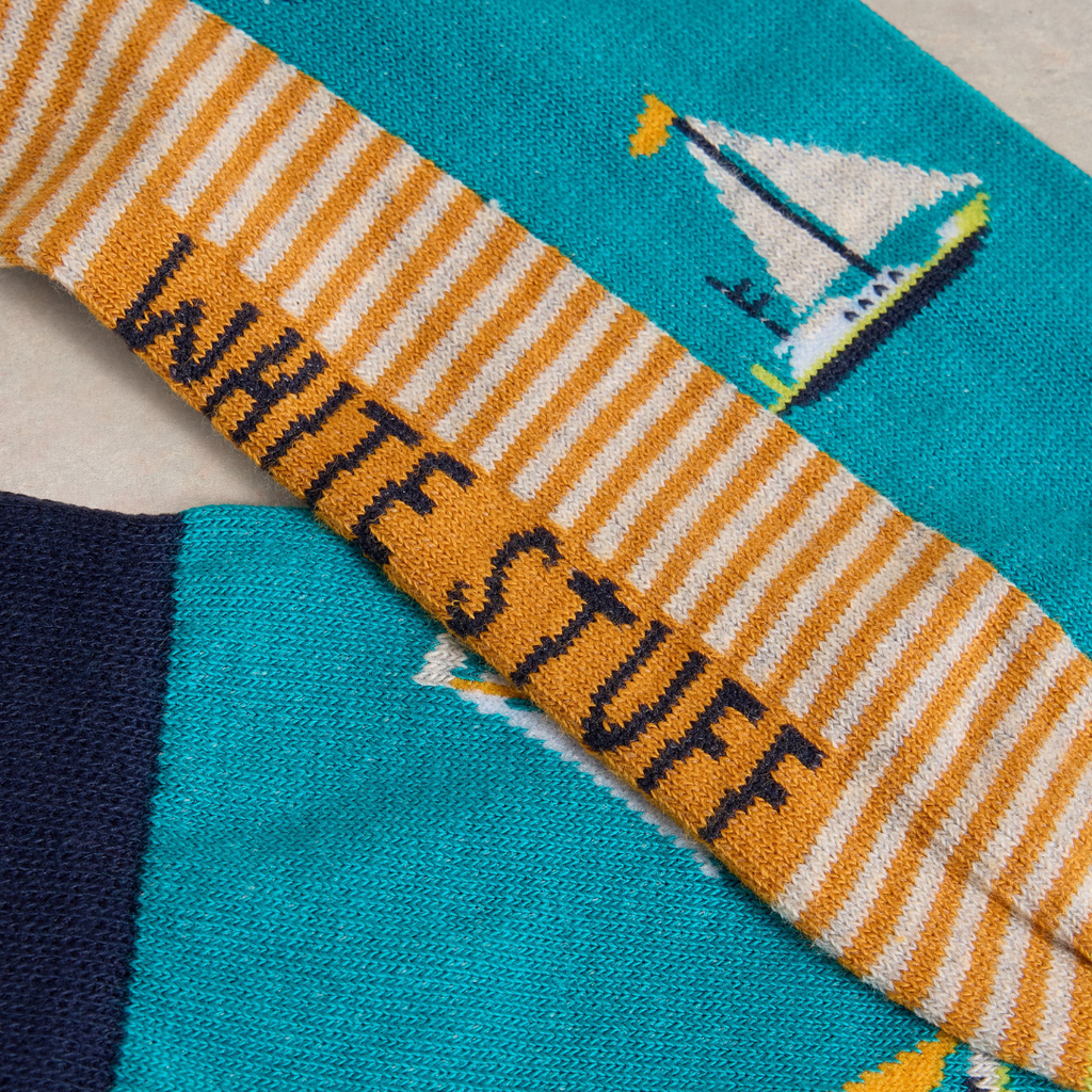 Pair of teal and navy socks with a mustard yellow and white striped section featuring the words "White Stuff" and sailboat