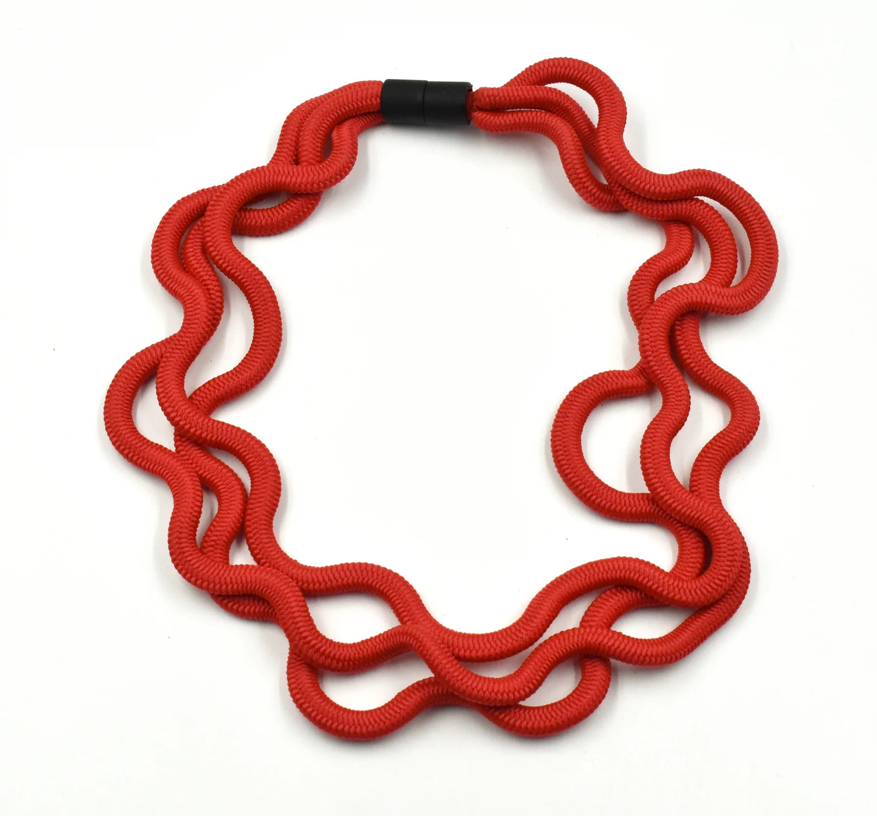A red triple cord necklace with black clasp sat on a white background