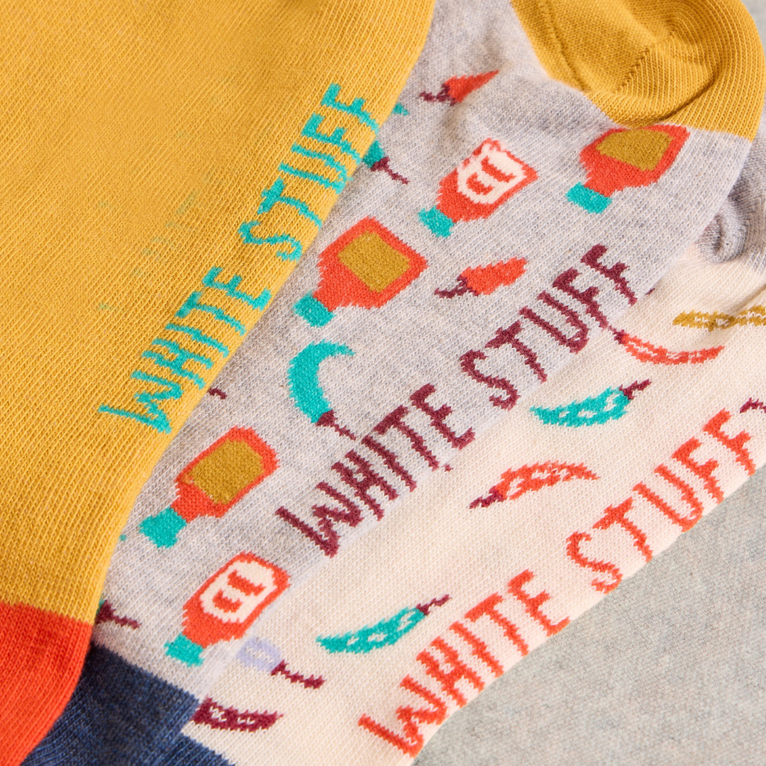 Three pairs of crew socks with "White Stuff" text and illustrated hot sauce bottles and chili peppers.
