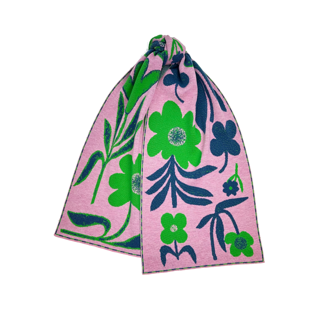 Pink knitted scarf with a bold floral pattern in green and navy blue.