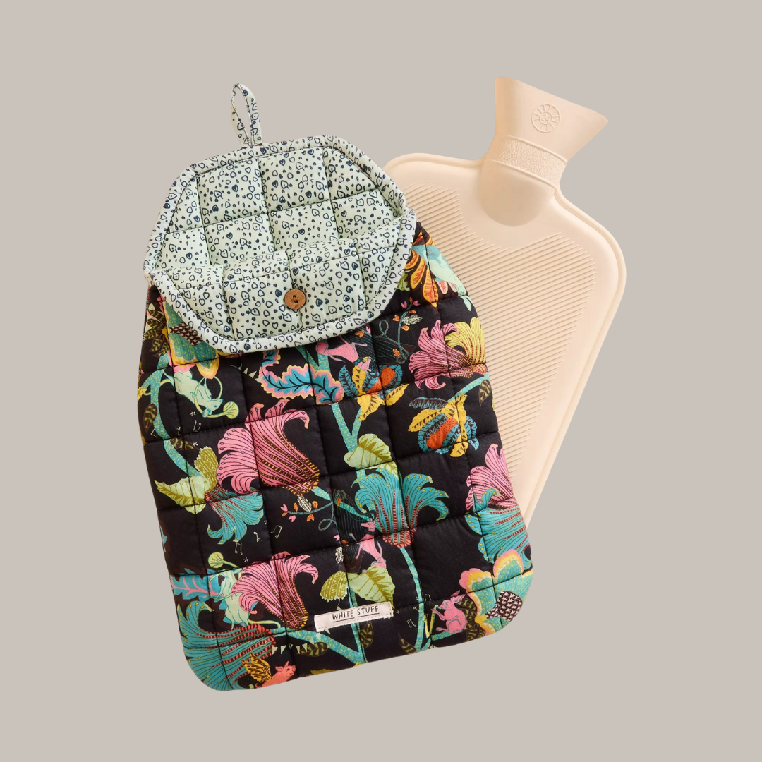 Floral quilted hot water bottle cover with a pale green patterned inner flap and beige rubber hot water bottle.