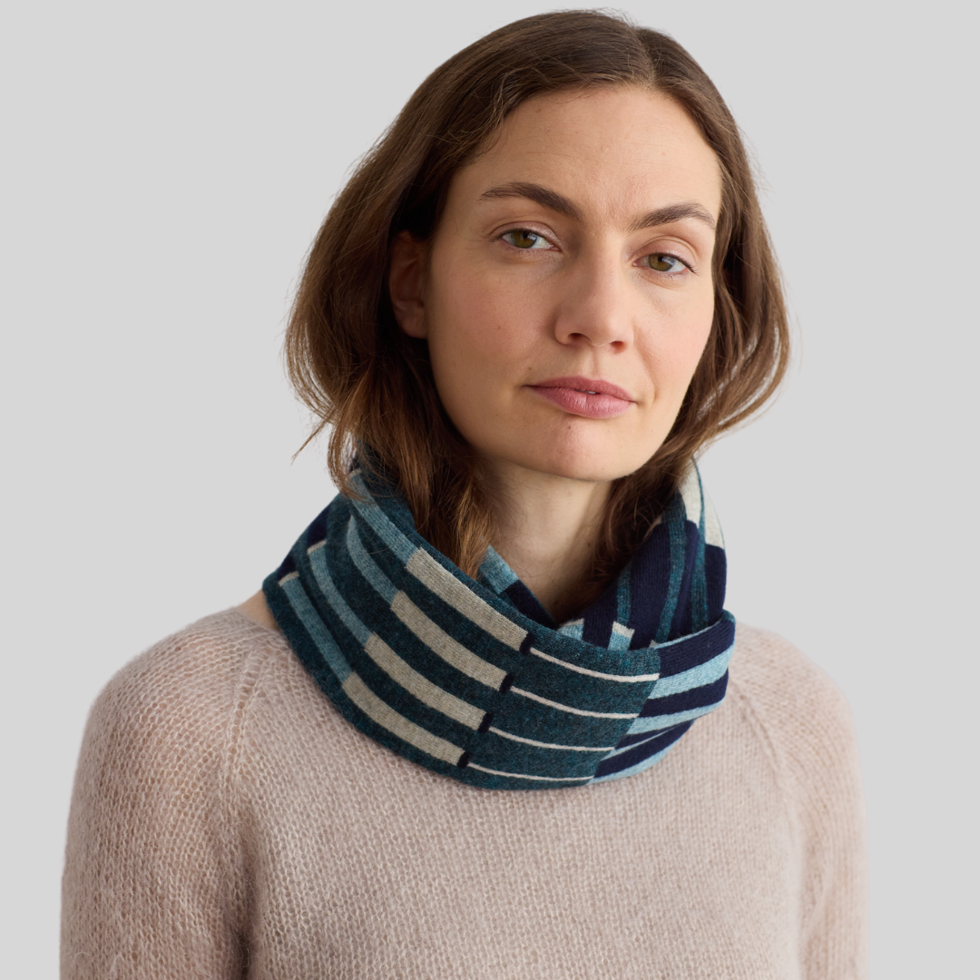 Teal and cream striped knit infinity scarf.  The scarf is folded double and worn around the neck.